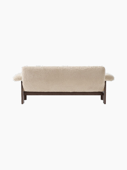 A back view of the Brasilia Sofa, upholstered in cream sheepskin, revealing its plush, textured back and dark wooden frame.