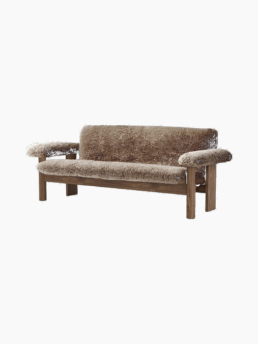 The Brasilia Sofa in brown sheepskin, shown from the front. It has a dark wood frame, low back and large rounded armrests.
