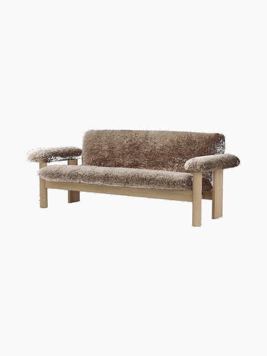 A front-angle view of the Brasilia Sofa, upholstered in plush brown sheepskin with a solid natural oak frame.