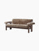 The Brasilia Sofa, upholstered in thick brown sheepskin, with a dark wood frame featuring chunky, rounded legs and armrests.
