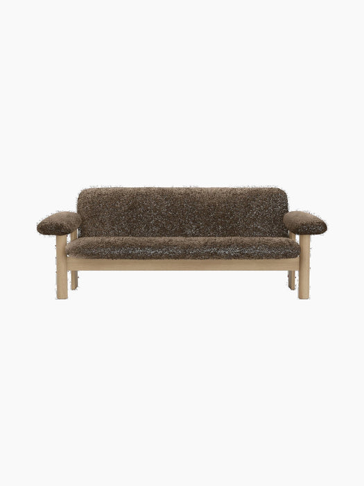 A front view of the two-seater Brasilia Sofa, upholstered in dark brown sheepskin with a solid natural oak frame.