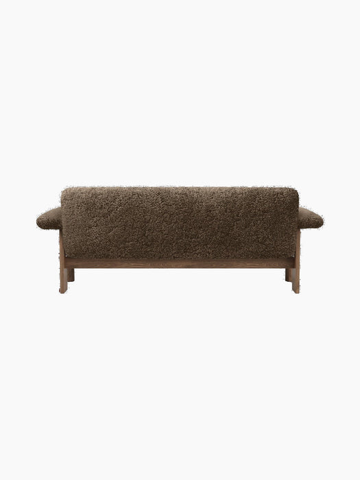 A rear view of the Brasilia Sofa, showcasing its textured brown sheepskin upholstery, wooden base, and prominent armrests.