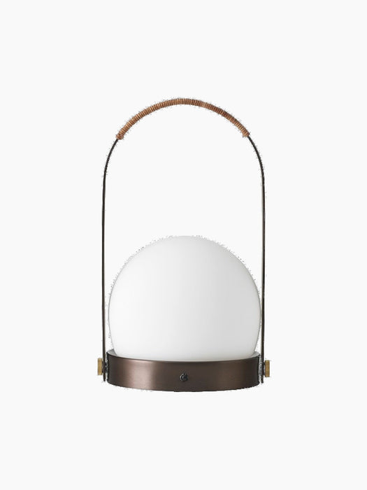 Front view of the Carrie Table Lamp in bronzed brass, featuring a white opal glass orb and a handle wrapped in brown leather.