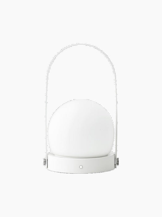 A back view of the white Carrie Table Lamp. It features a glowing glass orb on a round base with a slim, arched handle.