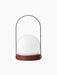 Back view of the portable Carrie Table Lamp in Burned Red, featuring a slim handle arching over a glowing white glass orb.