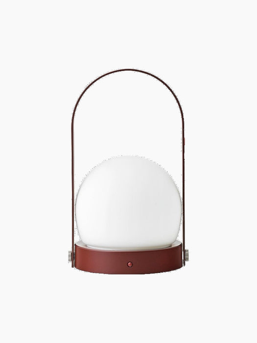 Front view of the Carrie Table Lamp, Portable, in Burned Red. It features a white glass shade on a red base and handle.