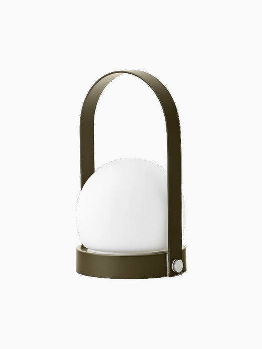 An angle view of the Carrie Portable Table Lamp in olive green, with a basket-like base, arched handle and white glass orb.