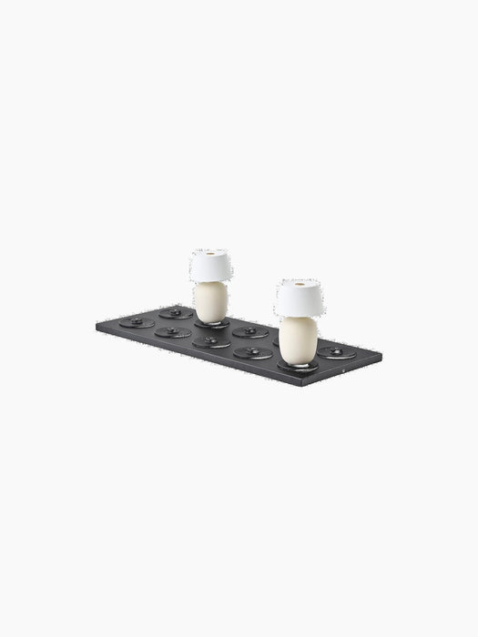 A black Charging Board with eight ports shown at an angle, with two portable ivory lamps with white shades charging.