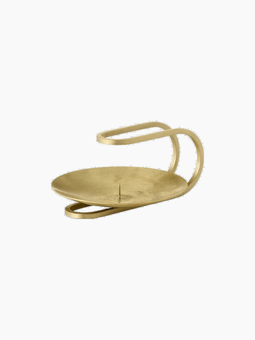 The sculptural Clip Candle Holder in brushed brass, featuring a circular tray with a candle spike and looped handle.