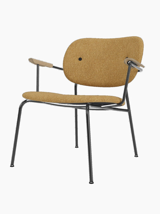 A Co Lounge Chair, fully upholstered in mustard yellow Moss fabric, with a black steel frame and natural oak armrests.