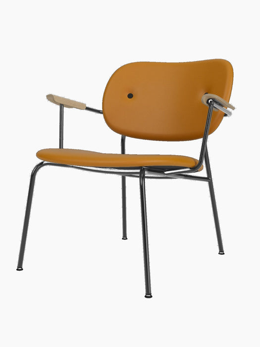 Front three-quarter view of the Co Lounge Chair, upholstered in tan Dakar leather with natural oak arms and black frame.