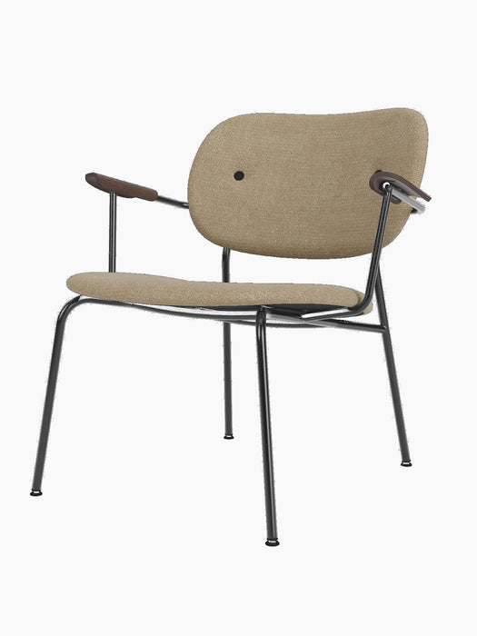 The Co Lounge Chair, fully upholstered in light brown Bouclé fabric, with a black steel frame and dark stained oak armrests.