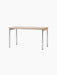 The rectangular Co Table, seen from an angle, with a creme laminate top, oak wood apron, and slender, shiny chrome legs.
