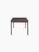 A side profile of the rectangular Co Table with dark terra laminate top, a solid oak trim apron, and thin black steel legs.