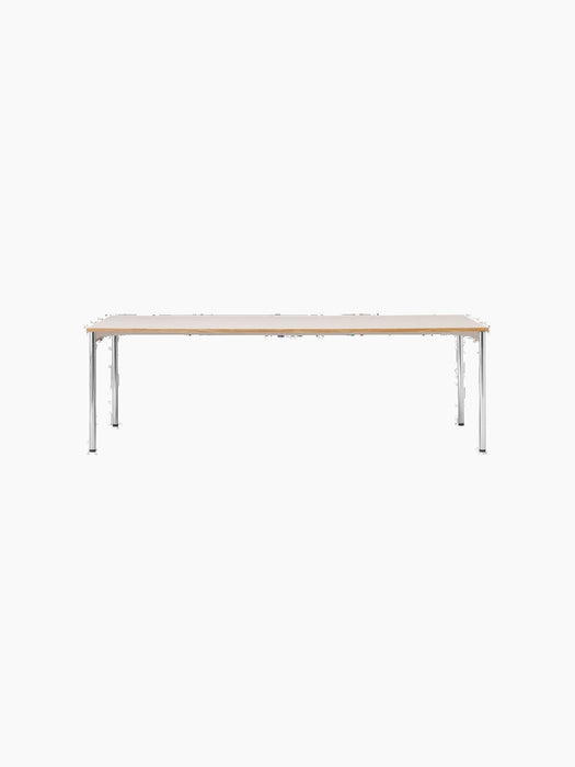 A front view of the rectangular Co Table, featuring a creme laminate top with solid oak trim and slender, chromed steel legs.