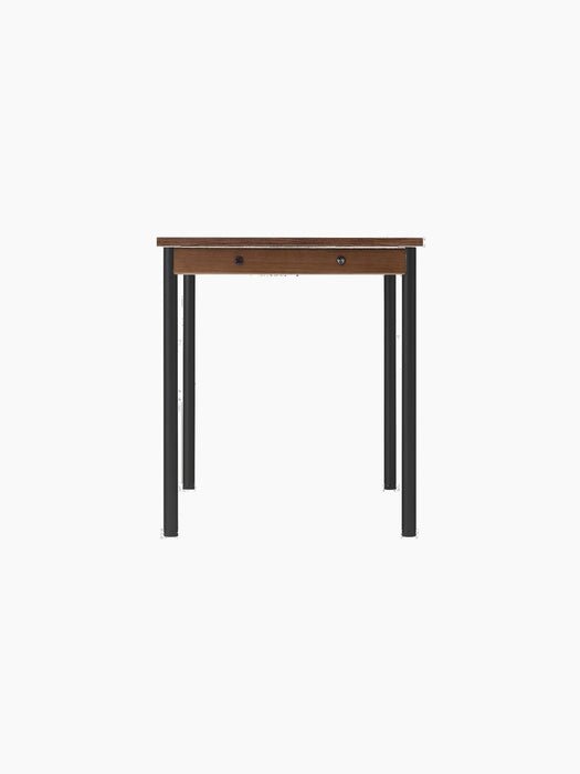 A front-on view of the rectangular Co Table, featuring a dark wood-grain laminate top and slender black steel legs.