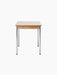 Side view of the Co Table, showing its creme laminate top, solid oak apron with decorative screws, and chromed legs.