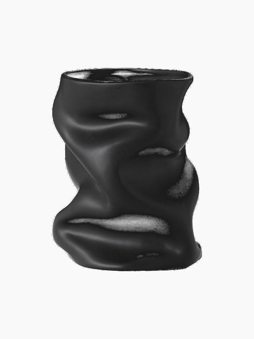 Angled view of the sculptural Collapse Vase in matte black. Its body is artfully crumpled and folded, creating soft shadows.