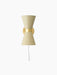 The cream Collector Wall Lamp, front view. Hourglass-shaped with perforated shades, a brass band, and a white power cord.