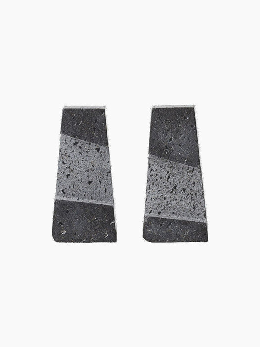 Studio shot of two trapezoid-shaped Converge Book Ends in dark lava stone, standing apart against a plain black background.