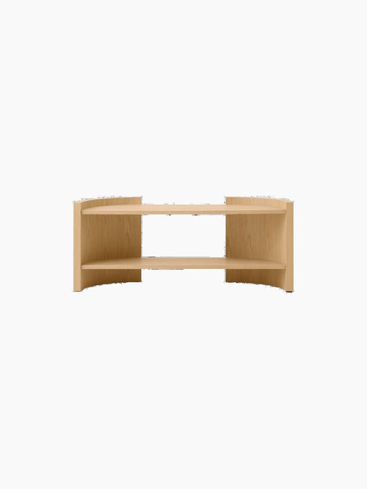 Front view of a low, curved, two-tiered console table in a light oak finish, set against a solid black background.