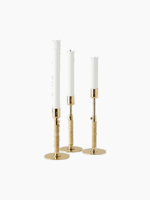 The Duca Candle Holder collection in polished brass. Three holders of varying heights with textured stems and white candles.