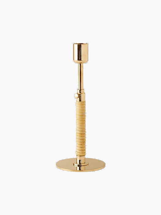 The Duca Candleholder in polished brass. It has a round base, an adjustable stem with a knob, and a rattan-wrapped handle.