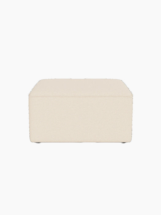 Eave Modular Pouf, 75, a square ottoman upholstered in a textured, light beige Logan Jasmine fabric on a black background