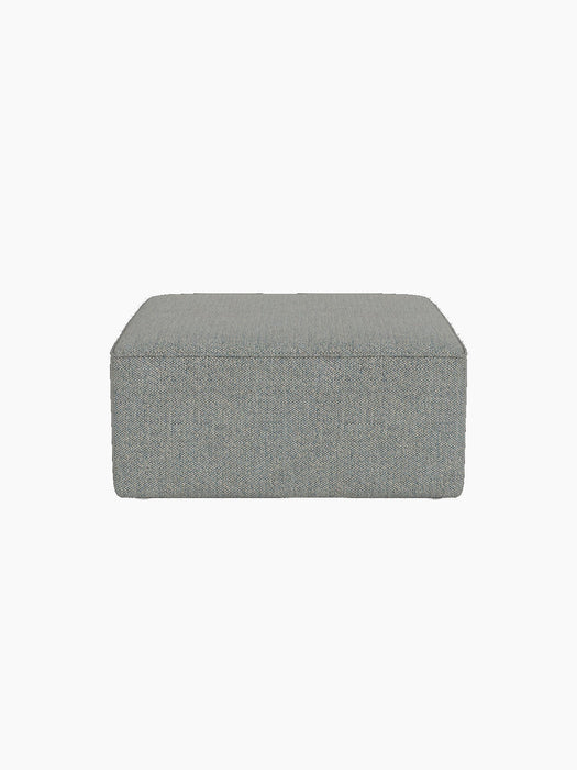 Front view of the Eave Modular Sofa, 86, Pouf upholstered in a textured light blue Safire fabric, against a black background.
