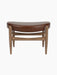 Front view of the Elizabeth Ottoman with a curved brown leather seat and a solid walnut frame on a black background.