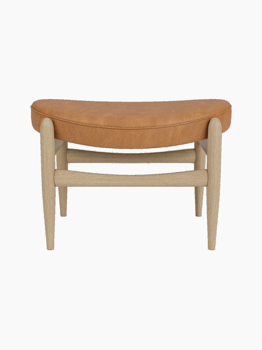 A front view of the Elizabeth Ottoman, featuring a curved seat upholstered in Dunes Cognac leather on a natural oak frame.