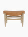A front view of the Elizabeth Ottoman, featuring a curved seat upholstered in Dunes Cognac leather on a natural oak frame.