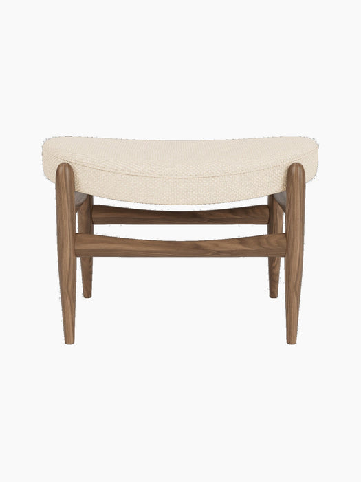A front view of the Elizabeth Ottoman with a walnut wood frame and curved cushion upholstered in cream Logan Jasmine fabric.