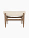 A front view of the Elizabeth Ottoman with a walnut wood frame and curved cushion upholstered in cream Logan Jasmine fabric.