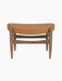 Front view of the Elizabeth Ottoman. The piece has a walnut frame and a curved top cushion upholstered in cognac leather.