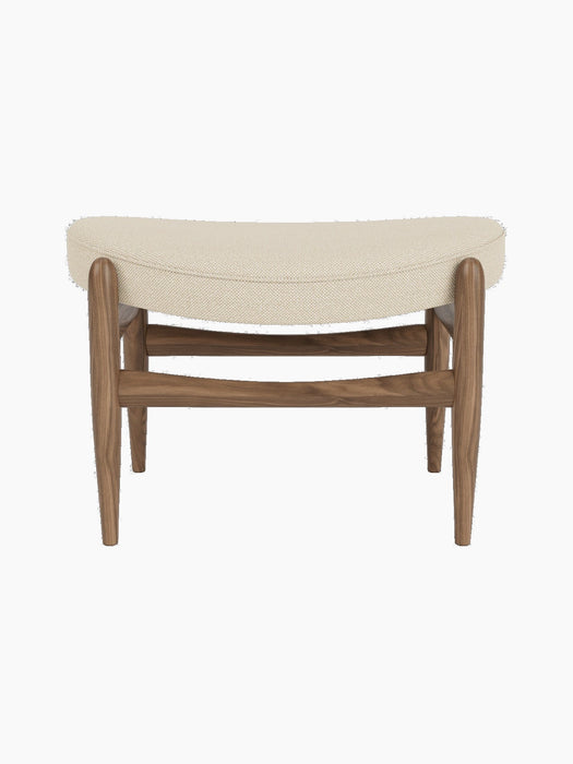 A front view of the Elizabeth Ottoman, with a walnut frame and a curved cushion upholstered in light Hallingdal fabric.