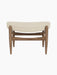 A front view of the Elizabeth Ottoman, with a walnut frame and a curved cushion upholstered in light Hallingdal fabric.