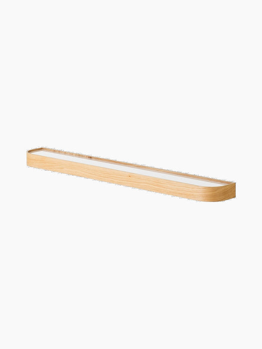 Angled view of the Ray Wall Lamp in natural oak. Long, slim lamp with minimalist design, light wood frame and diffuser.