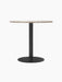 Harbour Column Dining Table with a round Kunis Breccia stone top on a slender black pedestal with a circular base.