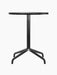 Front view of the Harbour Column Dining Table. It features a round, charcoal linoleum top and a black, four-legged starbase.