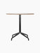 A front view of the Harbour Column Dining Table with a round Kunis Breccia stone top and black metal star-shaped base.