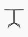A front view of the Harbour Column Dining Table, featuring a round charcoal linoleum top and a slender black metal star base.