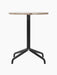 A front view of the Harbour Column Dining Table, featuring a round Kunis Breccia stone top and a black four-legged star base.