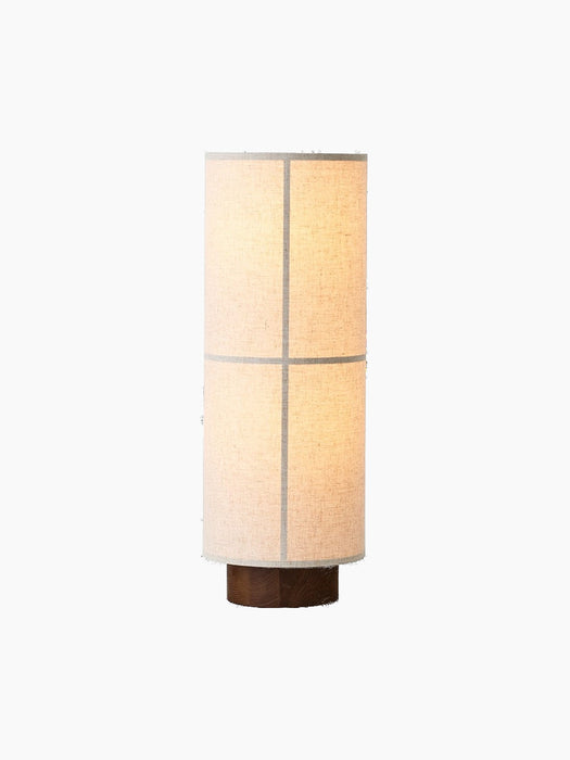An angled view of the lit Hashira Floor Lamp in Raw. The lamp features a textured linen shade and a dark wood base.