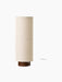A front-on view of the Hashira Floor Lamp in Raw, with a tall, cylindrical, raw-coloured linen shade and dark wood base.