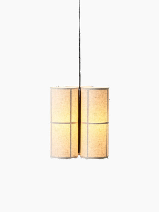 The Hashira Pendant Lamp, Cluster. Three cylindrical linen shades are lit, glowing warmly against a black background.