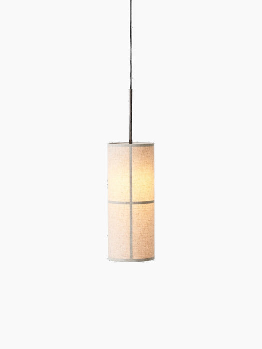 An angled view of the Hashira Pendant Lamp, illuminated, with its raw linen shade and graphic frame on a black background.
