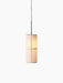 An angled view of the Hashira Pendant Lamp, illuminated, with its raw linen shade and graphic frame on a black background.