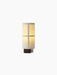 Hashira Portable Table Lamp, front view. Its illuminated raw linen shade reveals a grid frame and sits on a dark ash base.