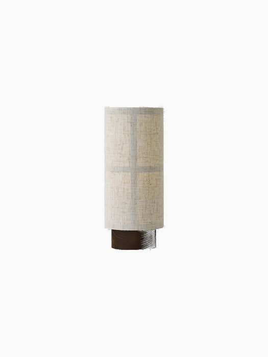Front view of the Hashira Table Lamp, Portable. The lamp is off, with a cylindrical raw linen shade on a dark ash wood base.